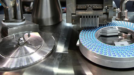 A photograph of a drug manufacturing process where theraputic tablets are being produced