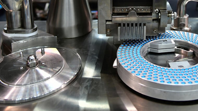 A photograph of a drug manufacturing process where theraputic tablets are being produced