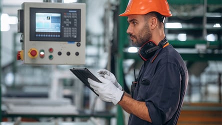 A photograph of a CNC operator using a tablet to access analytics with real-time data in manufacturing