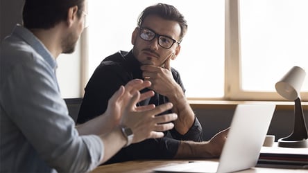 A photograph of two manufacturing professionals, one explaining the difference between BPO, BPM, and BSO