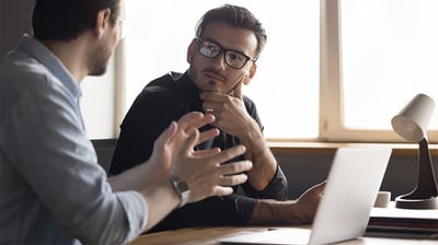 A photograph of two manufacturing professionals, one explaining the difference between BPO, BPM, and BSO