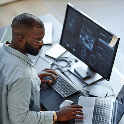 Manufacturing software engineer using two computers to perform system implementation and systems integration.