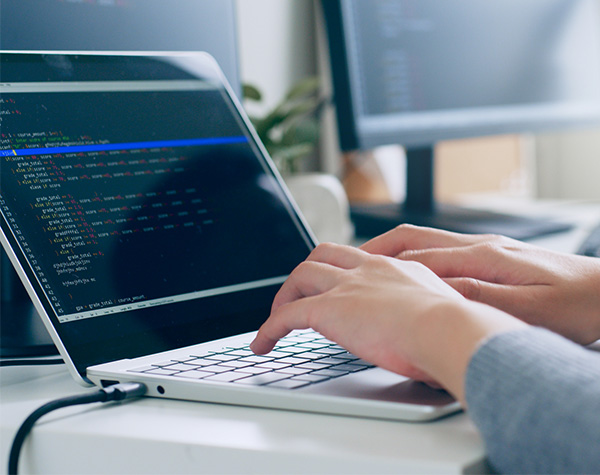 Application programmer working on a laptop that displays computer code