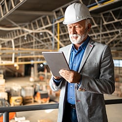 A business consultant using a tablet to take notes about the processes that happen in the manufacturing plant.