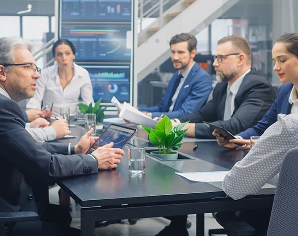 Business leaders in a conference room discussing which projects have the most impact to the manufacturing company.