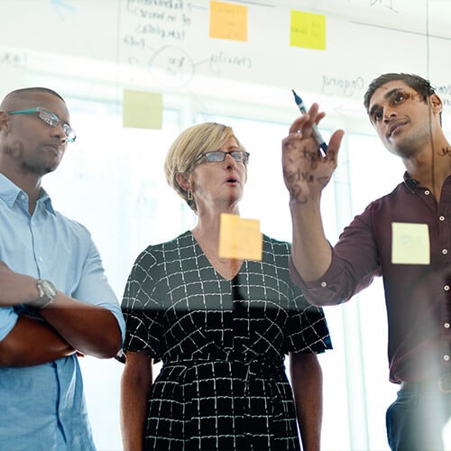 A group of business people examining capacity, material flow, bottlenecks, and demand planning. 