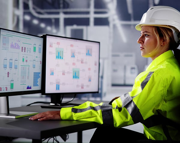 Photograph of manufacturing engineer looking at computer screens to make decisions from machine data.
