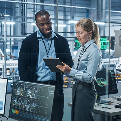 Photograph of an IT engineer and a manufacturing leader looking at a tablet device to see how existing manufacturing applications work together.