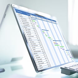 Photograph of a laptop screen displaying production schedule optimization with a gantt chart.