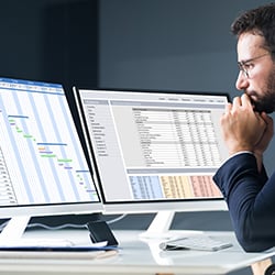 Photograph of a project manager reviewing gantt charts for better resource optimization in project management.
