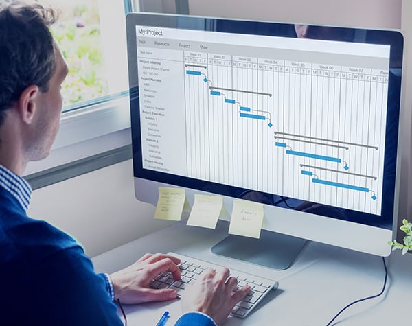 Photograph of a project management system and project manager reviewing project timelines.